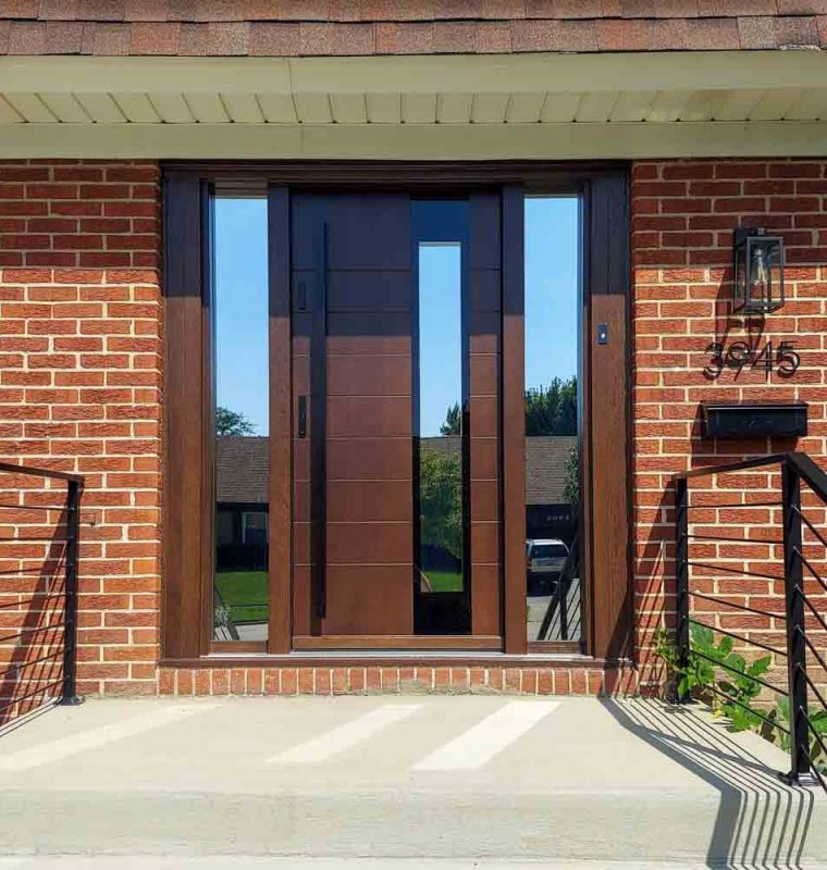 Main door of a house made of wood with two sidelights having reflective glass, a metal bar handle and two locksets